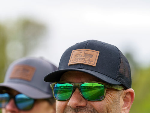 Two people wearing sunglasses and caps with visible brand logos outdoors.